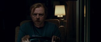 Movie still from “Paul” (2011), directed by Greg Mottola – A man sitting in a chair in front of a lamp; Close Up shot, Over the shoulder angle