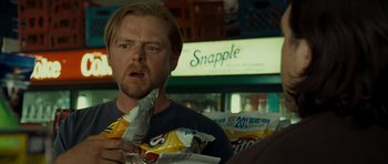 Movie still from “Paul” (2011), directed by Greg Mottola – A man is holding a bag of potato chips in front of him; Close Up shot, Over the shoulder angle