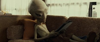 Movie still from “Paul” (2011), directed by Greg Mottola – An alien sitting on a couch looking at a tablet computer; Medium shot, High angle