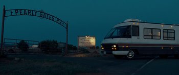 Movie still from “Paul” (2011), directed by Greg Mottola – A bus driving down a road next to a street sign at night; Extreme Wide shot, Low angle