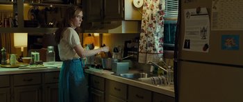 Movie still from “Paul” (2011), directed by Greg Mottola – A woman standing in a kitchen preparing a meal; Medium shot, Over the shoulder angle