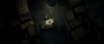 Movie still from “Paul” (2011), directed by Greg Mottola – An overhead view of a desk and chair in a dark room; Extreme Wide shot, Overhead angle