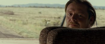 Movie still from “Paul” (2011), directed by Greg Mottola – A person sitting in a chair near a field; Close Up shot, Over the shoulder angle