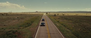 Movie still from “Paul” (2011), directed by Greg Mottola – Two cars driving down the middle of a road; Extreme Wide shot, High angle