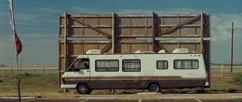 Movie still from “Paul” (2011), directed by Greg Mottola – An rv parked in front of a wooden building; Extreme Wide shot, Low angle