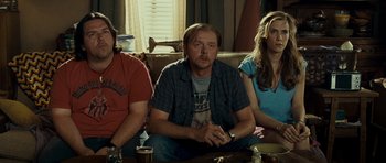 Movie still from “Paul” (2011), directed by Greg Mottola – A man sitting on a couch next to two other people; Medium shot, Over the shoulder angle