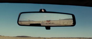 Movie still from “Paul” (2011), directed by Greg Mottola – A rear view mirror of a truck driving down a road; Extreme Wide shot, Over the shoulder angle