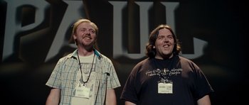 Movie still from “Paul” (2011), directed by Greg Mottola – Two men standing next to each other on a stage; Medium shot, Over the shoulder angle