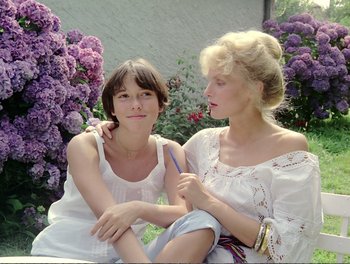 Two young women sitting next to each other in front of flowers