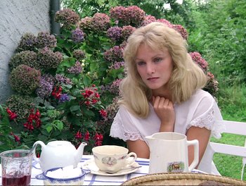 A woman sitting at a table in front of a tea set