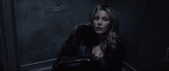 Movie still from “Payback” (1999), directed by Brian Helgeland – A woman in a leather jacket sitting in front of a wall; Close Up shot, Overhead angle