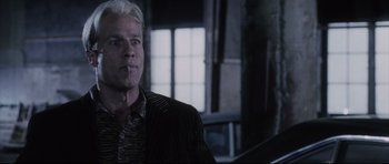 Movie still from “Payback” (1999), directed by Brian Helgeland – A man in a striped jacket sitting in front of a window; Close Up shot, Low angle