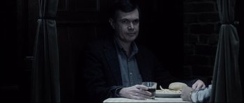 Movie still from “Payback” (1999), directed by Brian Helgeland – A man sitting at a dinner table holding a glass of wine; Medium shot, Over the shoulder angle