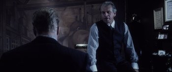 Movie still from “Payback” (1999), directed by Brian Helgeland – A man in a suit and tie sitting next to another man; Medium shot, Over the shoulder angle