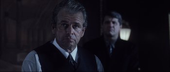 Movie still from “Payback” (1999), directed by Brian Helgeland – A man in a suit and tie standing next to another man in a suit and tie; Close Up shot, Over the shoulder angle