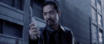 Movie still from “Payback” (1999), directed by Brian Helgeland – A man holding a cell phone while wearing a black shirt; Close Up shot, Low angle