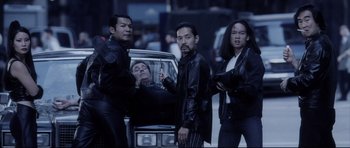 Movie still from “Payback” (1999), directed by Brian Helgeland – A group of men standing next to each other near a car; Medium shot, High angle