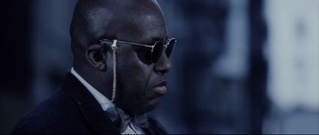 Movie still from “Payback” (1999), directed by Brian Helgeland – A person wearing a suit and sunglasses; Close Up shot, Low angle