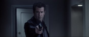 Movie still from “Payback” (1999), directed by Brian Helgeland – A man holding a gun while standing in a room; Close Up shot, Low angle