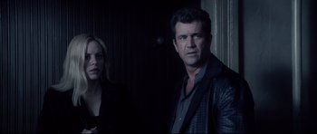 Movie still from “Payback” (1999), directed by Brian Helgeland – A man and a woman standing next to each other in front of a door; Medium shot, Over the shoulder angle