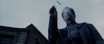 Movie still from “Payback” (1999), directed by Brian Helgeland – A man is throwing something in the air in front of a building; Close Up shot, Low angle