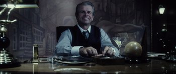 Movie still from “Payback” (1999), directed by Brian Helgeland – An older man sitting at a table with a glass of wine; Medium shot, Low angle