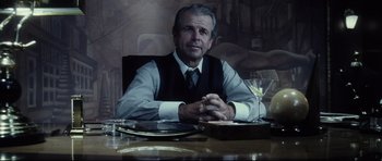 Movie still from “Payback” (1999), directed by Brian Helgeland – An older man sitting at a table with a glass of wine in front of him; Medium shot, Over the shoulder angle