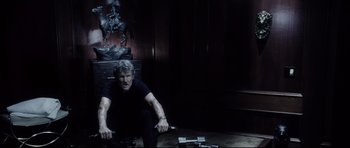 Movie still from “Payback” (1999), directed by Brian Helgeland – A man sitting on the ground in front of a statue; Medium shot, Low angle