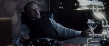 Movie still from “Payback” (1999), directed by Brian Helgeland – A man sitting at a desk in a dark room; Medium shot, Low angle