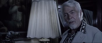 Movie still from “Payback” (1999), directed by Brian Helgeland – An older man sitting in front of a white lamp; Close Up shot, Over the shoulder angle