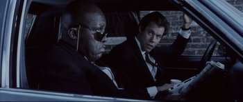 Movie still from “Payback” (1999), directed by Brian Helgeland – Two men sitting in the back seat of a car; Medium shot, Low angle
