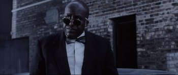 Movie still from “Payback” (1999), directed by Brian Helgeland – A man in a suit and bow tie wearing sunglasses; Close Up shot, Low angle