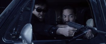 Movie still from “Payback” (1999), directed by Brian Helgeland – A man holding a gun in the back seat of a car; Medium shot, Low angle