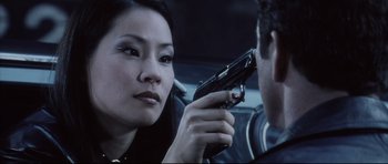 Movie still from “Payback” (1999), directed by Brian Helgeland – A woman holding a gun up to her face; Close Up shot, Over the shoulder angle