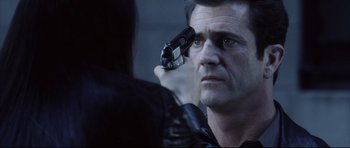 Movie still from “Payback” (1999), directed by Brian Helgeland – A man holding a gun up to his eye; Close Up shot, Over the shoulder angle