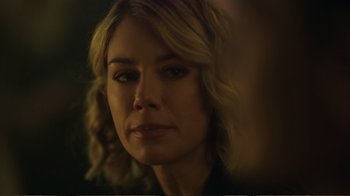 Movie still from “Peacemaker” (2022), created by James Gunn – A woman with blonde hair looking at the camera; Close Up shot, Over the shoulder angle