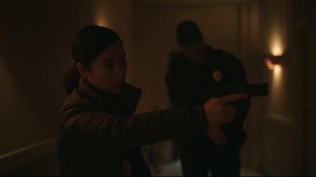 Movie still from “Peacemaker” (2022), created by James Gunn – A woman holding a gun in a dark room; Medium shot, Low angle