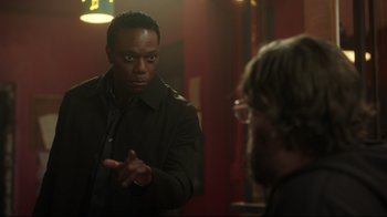 Movie still from “Peacemaker” (2022), created by James Gunn – A man is talking to another man in front of a mirror; Medium shot, Over the shoulder angle