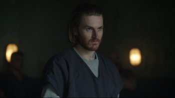 Movie still from “Peacemaker” (2022), created by James Gunn – A man with long hair wearing a gray shirt; Close Up shot, Over the shoulder angle