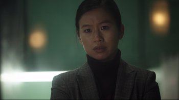 Movie still from “Peacemaker” (2022), created by James Gunn – A woman in a suit looking at the camera; Close Up shot, Low angle