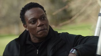 Movie still from “Peacemaker” (2022), created by James Gunn – A person wearing a black jacket; Close Up shot, Over the shoulder angle