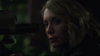 Movie still from “Peacemaker” (2022), created by James Gunn – A beautiful woman with blonde hair and blue eyes looking at the camera; Close Up shot, Over the shoulder angle