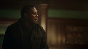 Movie still from “Peacemaker” (2022), created by James Gunn – A man in a black jacket is looking off into the distance; Close Up shot, Over the shoulder angle