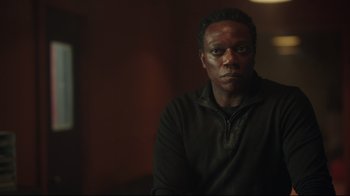 Movie still from “Peacemaker” (2022), created by James Gunn – A man in a black shirt is looking at the camera; Close Up shot, Low angle