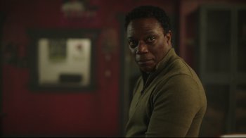 Movie still from “Peacemaker” (2022), created by James Gunn – A man in a green shirt is looking at the camera; Close Up shot, Low angle