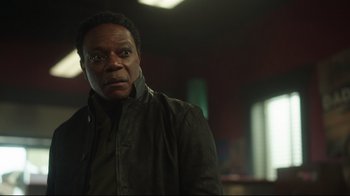 Movie still from “Peacemaker” (2022), created by James Gunn – A man standing in a dark room with his eyes wide open; Close Up shot, Low angle