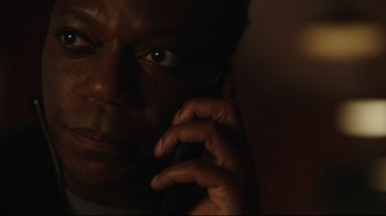 Movie still from “Peacemaker” (2022), created by James Gunn – A person talking on a cell phone; Close Up shot, Low angle