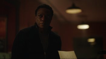 Movie still from “Peacemaker” (2022), created by James Gunn – A man standing in a dark room holding a piece of paper; Close Up shot, Over the shoulder angle
