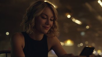 Movie still from “Peacemaker” (2022), created by James Gunn – A beautiful blonde woman sitting in a room; Close Up shot, Over the shoulder angle