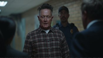 Movie still from “Peacemaker” (2022), created by James Gunn – A man in plaid shirt standing next to a police officer; Close Up shot, Over the shoulder angle